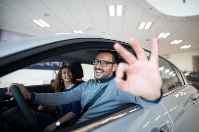 happy-customer-buying-new-car-at-dealership-min